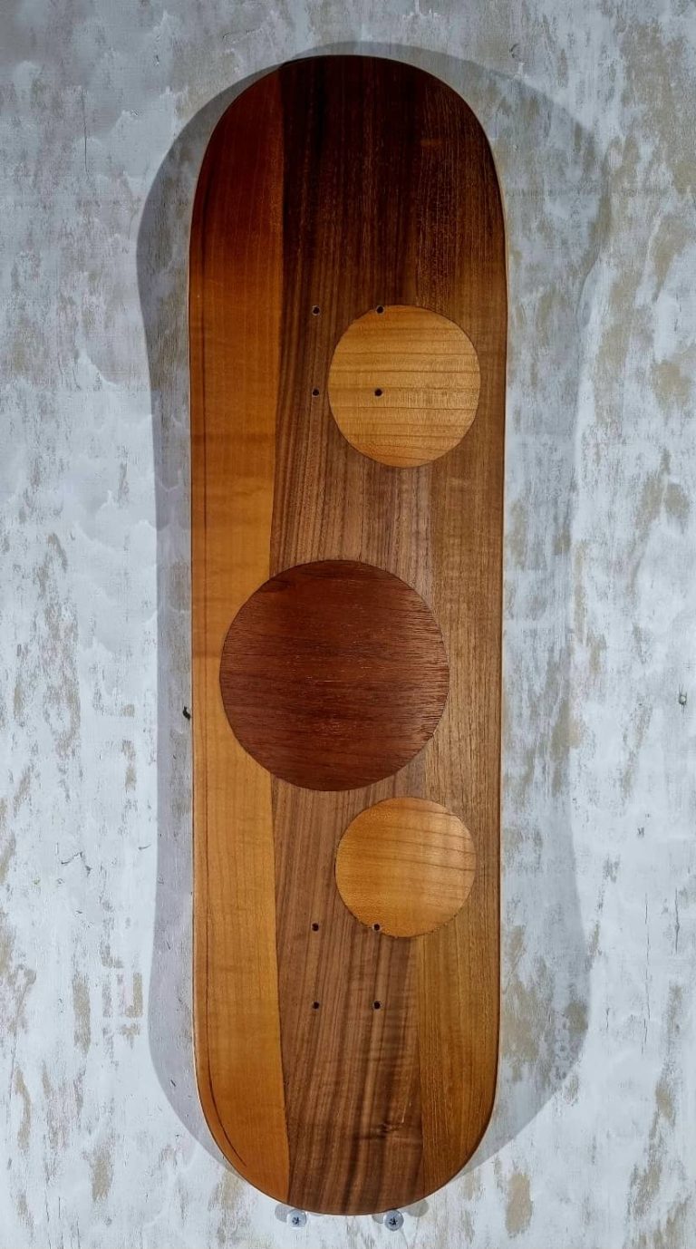 Planche de skateboard, street shape, customisée par marquetterie abstraite de ronds et lignes entrecoupées, mariant les essences de bois type acajou, noyer, merisier