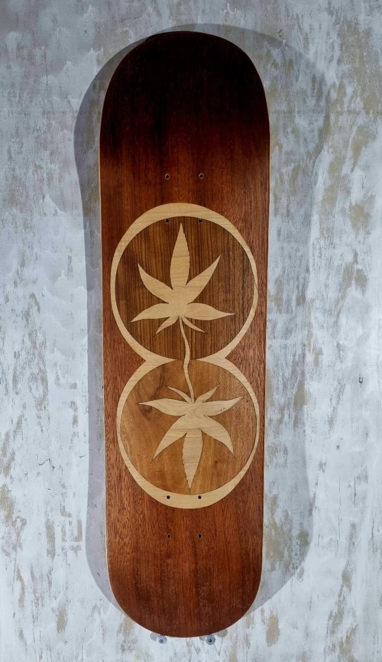planche de skate artisanale, dotée d'une marquetterie d'acajou, merisier, accacia, représantant deux feuilles de chanvre stylisées