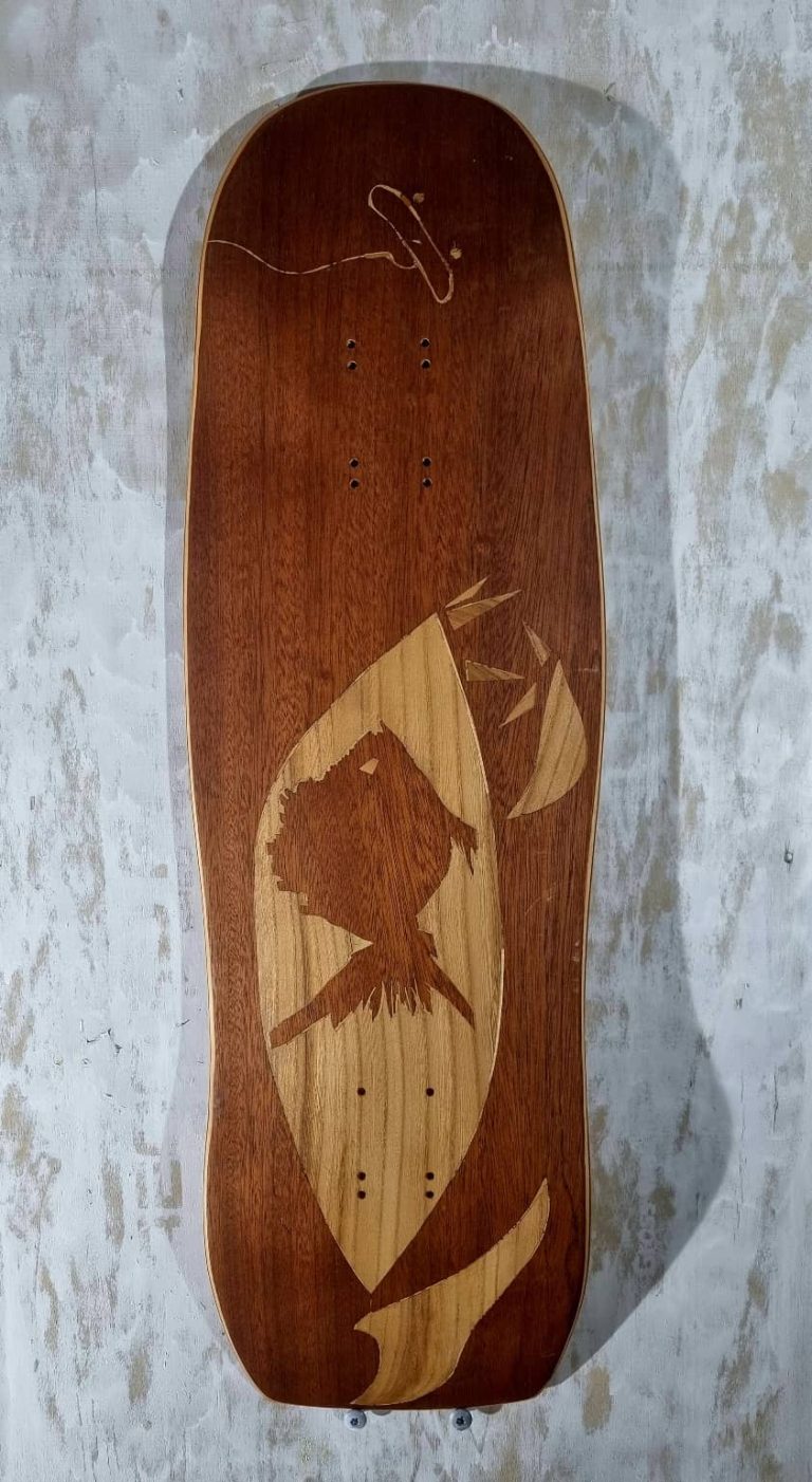 Planche de skate avec marquetterie acajou et merisier, représentant des poissons prêts à dévorer une board accrochée à un hameçon. shape old school