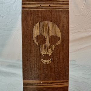 vue de dessus de l'oeuvre unique Pyébwa Skateboards. une marquetterie aux essences de bois luxe dévoile une tête de mort en zébrano sur acajou et merisier.