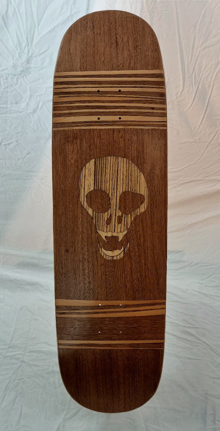 vue de dessus de l'oeuvre unique Pyébwa Skateboards. une marquetterie aux essences de bois luxe dévoile une tête de mort en zébrano sur acajou et merisier.